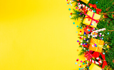 pine branches and colorful gift boxes on a yellow background top view. Space for the text.
