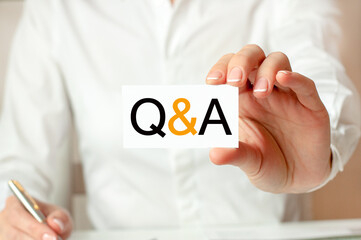 A woman in a white shirt holds a piece of paper with the text: Q and A. Business concept.