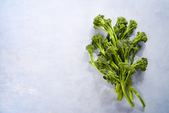 Broccolini fresh organic broccoli florets green vegetable baby broccoli, vegan raw healthy superfood on a light blue food background with empty copy space. Close-up. Top view, flat lay. © Mila Bond