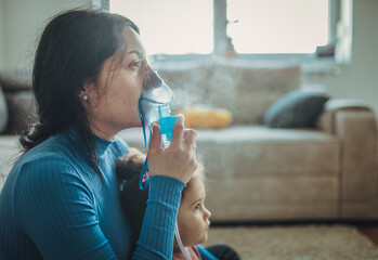 Mother helps her little girl to makes inhalation at home.During coronavirus COVID-19