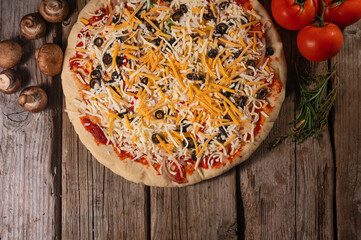 Italian pizza with ingredients mushrooms, tomatoes and herbs. Top view on wood background. Flat lay