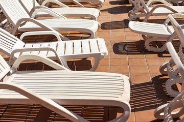 Empty white plastic sunbeds at holiday resort near pool, closeup detail