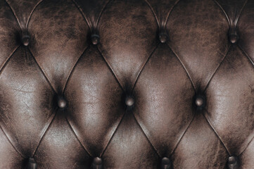 Dark brown leather sofa upholstery texture. The background surface is made of shiny luxury material...