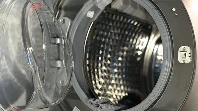 Woman playfully throwing dirty clothes into the washing machine from a distance. Doing laundry in a funny way.