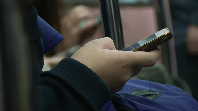 Close up on commuter's thumb scrolling expertly on the screen of a smartphone while sitting on a seat on the public transports, going to work