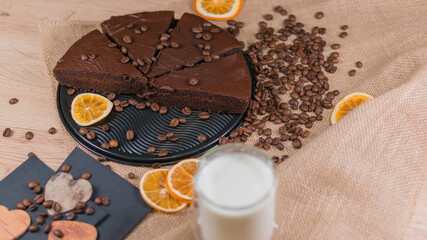 slices of chocolate brownie cake with glass of milk and coffee beanas on wooden table