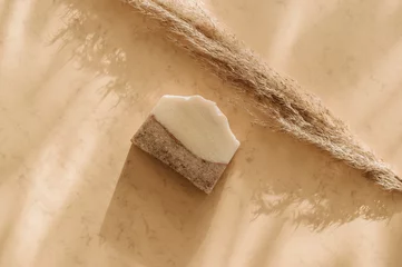 Handgemachte Seife und Pampasgras. Sonnenschirmschatten auf beigem Hintergrund. Zero Waste, umweltfreundliches Kosmetikkonzept. Vintage-Farbfilter © Augustas Cetkauskas
