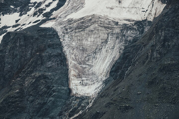 Nature background of big rocky snowy mountain wall with white glacier close up. Dark atmospheric natural texture of icy mountainside. Full frame of black white high mountains with ice on rockies.