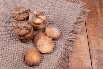 the cookies are stacked in piles, some are tied up, and some just lie on a gray rug with a fringe, against a background of a wooden surface