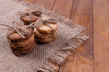 side view and a little top view of the gingerbread cookies, folded in piles and tied with a string, lie on a gray rug with fringed edges, and against the background of a wooden surface