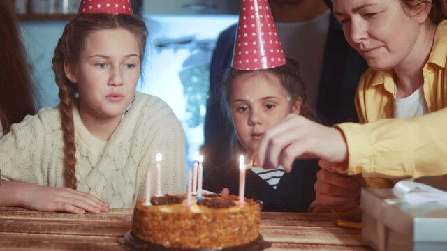 kid birthday. little girl blows out the candles on the cake in circle of happy family. celebration birthday kid concept. friendly happy family celebrating birthday a lot of people dream