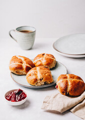 Traditional English Easter Hot Cross Buns on a plate with jam and tea cup