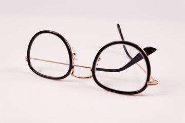 front view of round glasses that lie vertically, one arm is straightened slightly and the other is folded