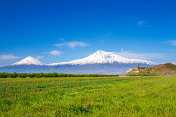 Fototapeta premium Awe-Inspiring medieval Khor Virap monastery in front of Mount Ararat viewed from Yerevan, Armenia. This snow-capped dormant compound volcano described in the Bible as the resting place of Noah's Ark.