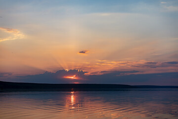 Dramatic sunset over sea water with cloudy sky