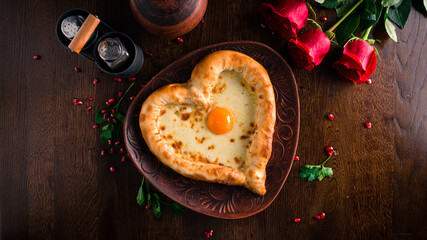 Valentines Day food. Heart shaped pizza, pie with cheese and egg in the shape of a heart and Red roses on the table