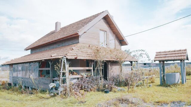 At the village. Old abandoned wooden house in a village. Motion camera view of the two-storey house standing at the country with autumn weather at the background. Farm life, village landscapes concept