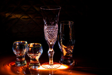 A set of wine glasses and glasses for strong drinks on the illuminated bar counter. Interior decoration of the bar.