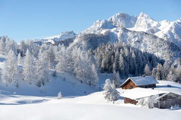 Fototapeta na wymiar Beautiful winter mountain landscape with snowy forest and traditional alpine chalet. Sunny frosty weather with clear blue sky 
