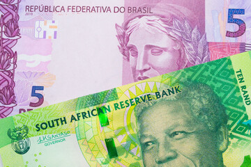 A macro image of a shiny, green 10 rand bill from South Africa paired up with a pink and purple five real bank note from Brazil.  Shot close up in macro.