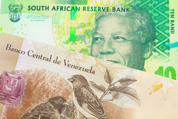 A macro image of a shiny, green 10 rand bill from South Africa paired up with a colorful one hundred Bolivar bank note from Venezuela.  Shot close up in macro.