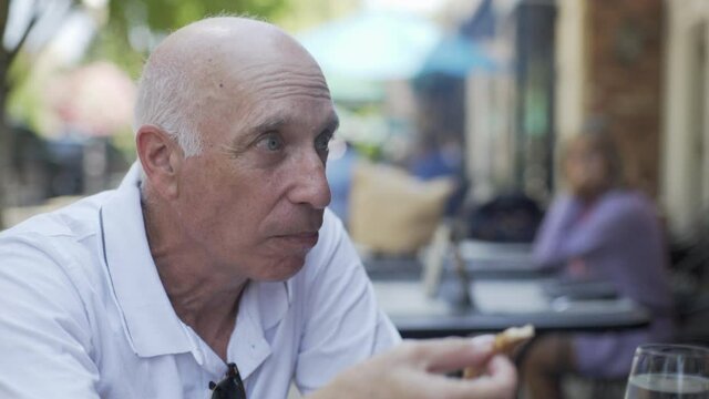 Caucasian Man Eating at a Restaurant Offers to Share his Food