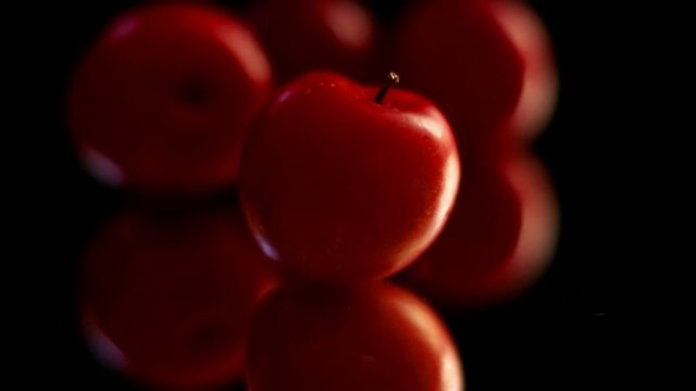 cereza roja y fresca sobre fondo negro , cae agua sobre ella; fruta con reflejo inferior. sin sonido