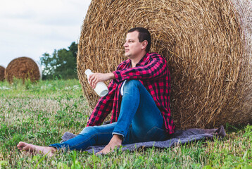 man drinks fresh bio milk on the field in the background, hay, grass, farm