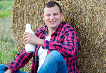 man drinks fresh bio milk on the field in the background, hay, grass, farm