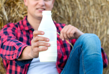 man drinks fresh bio milk on the field in the background, hay, grass, farm