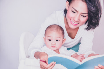 A picture of an Asian baby, not looking at a book and in a bored mood.