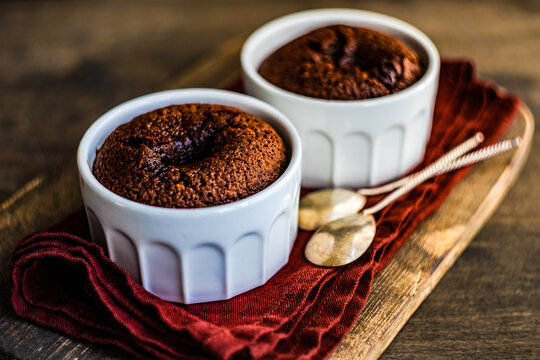 Close-up of two individual Chocolate fondant cakes on a wooden chopping board