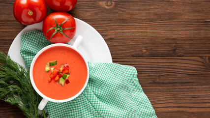 Delicious tomato soup with herbs on a wooden background. Top view.
