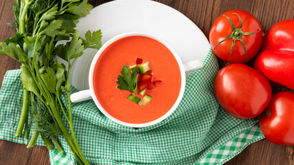 Delicious cream soup of tomatoes on a wooden background with herbs and croutons. In a soup bowl.
