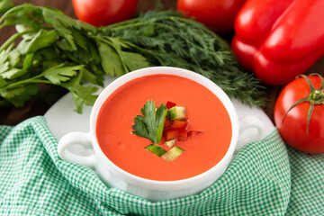 Delicious cream soup of tomatoes on a wooden background with herbs and croutons. In a soup bowl.