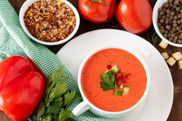 Tomato traditional tomato soup on a wooden background with different seasonings and herbs. Top view.