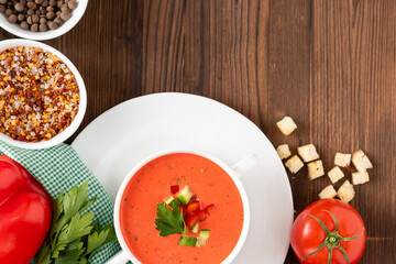 Tomato traditional tomato soup on a wooden background with different seasonings and herbs. Top view.
