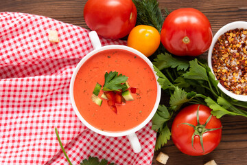 Spanish tomato gazpacho soup made from fresh tomatoes with various spices and herbs on a wooden background.