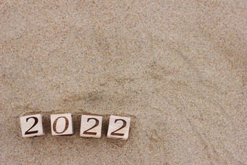 Wooden blocks with the numbers 2022 are located on the sand on the beach