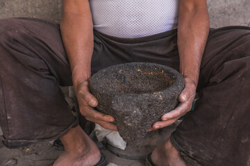 Detail of the craftsman's hands carving the stone to make molcajetes, traditional Mexican crafts to grind chili peppers, avocado or tomato for the elaboration of sauces. 