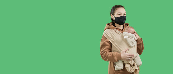 A tiny newborn baby in a baby sling, feeling protected from its beautiful mom in a protective face mask. The sling supports the child as an adult's hands, adapting to the baby's posture. Family lifes