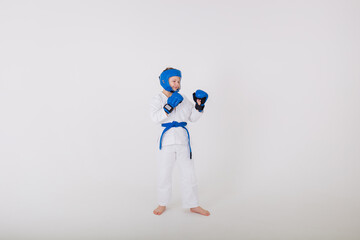 boy in a white kimono and wearing gloves and a helmet stands sideways on a white background with space for text
