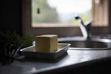 Block of butter on ceramic plate in kitchen