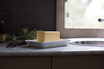 Block of butter on ceramic plate in kitchen