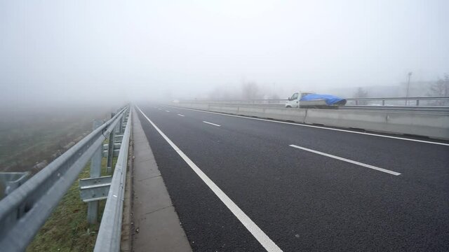 euroapean E5 foggy road with cars passing by Giurrgiu - Bucuresti, Bucharest Romania, winter 2021, road sign, right curve