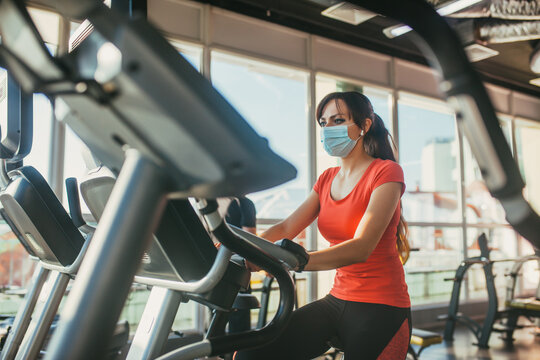 An active woman in a protective medical mask training in gym, during COVID-19 epidemic. Sport and quarantine.