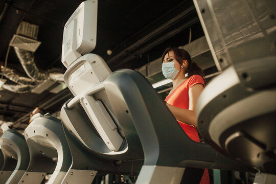 An active woman in a protective medical mask training in gym, during COVID-19 epidemic. Sport and quarantine.