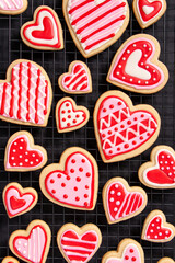 assortment of homemade heart shaped valentines sugar cookies with red, pink, and white icing designs
