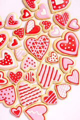 assortment of homemade heart shaped valentines sugar cookies with red, pink, and white icing designs