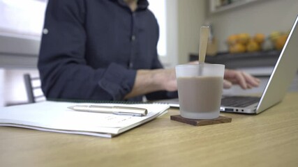 hands working on laptop with coffee in front middle-aged person working and drinking coffee. man hands working on gray laptop on wooden table
